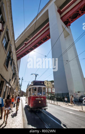 Hills Tramcar Tour tram beneath the Ponte 25 de Abril suspension bridge, Lisbon, Portugal. Stock Photo