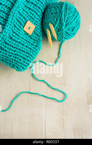turquoise  knitting work with knitting needles and a ball of wool on a wooden surface Stock Photo