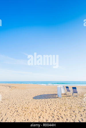 blue and white chairs and wind shelter at deserted beach Stock Photo