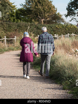 An elderly couple walking on path holding hands Stock Photo