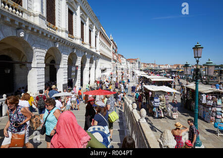 VENICE, ITALY - AUGUST 13, 2017: People and tourists in Venice walking with umbrellas under the sun near San Marco square in a sunny summer day in Ita Stock Photo