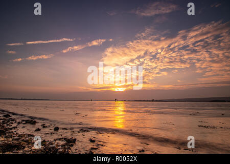 light rays through clouds at sunset on the shoreline Stock Photo