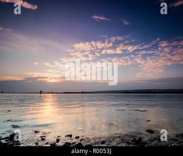 light rays through clouds at sunset on the shoreline Stock Photo