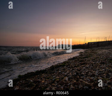 a calm beach sunset with small waves breaking over the sand Stock Photo