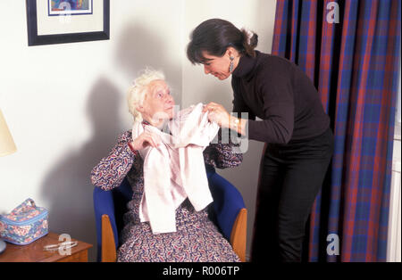 carer helping old lady to dress Stock Photo