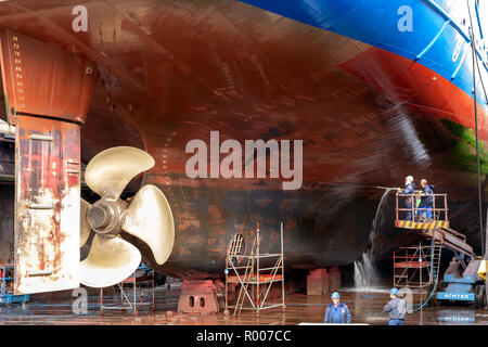 ROTTERDAM, NETHERLANDS - SEP 5, 2015: Dock workers at work on a vessel hull in a ship repair drydock. Stock Photo