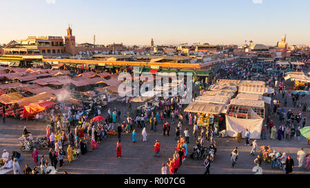 MARRAKESH, MOROCCO - APR 27, 2016: Tourists and locals on the Djemaa-el-Fna square during sunset in Marrakesh. Stock Photo