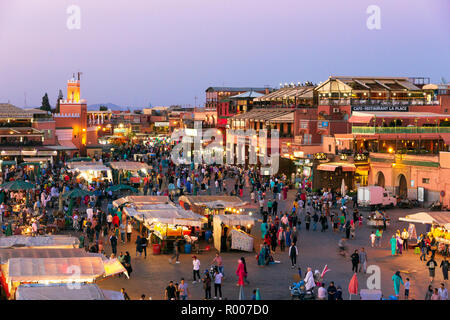 MARRAKESH, MOROCCO - APR 27, 2016: Tourists and locals on the Djemaa-el-Fna square during sunset in Marrakesh. Stock Photo