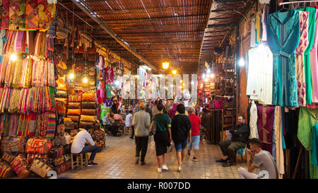 MARRAKESH, MOROCCO - APR 28, 2016: Tourists and local people walking through the shopping souks in the old medina of Marrakech. Stock Photo