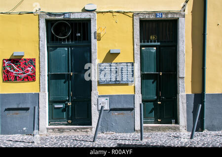 Yellow building facade with menu and closed doors in the Alfama district, Lisbon, Portugal. Stock Photo