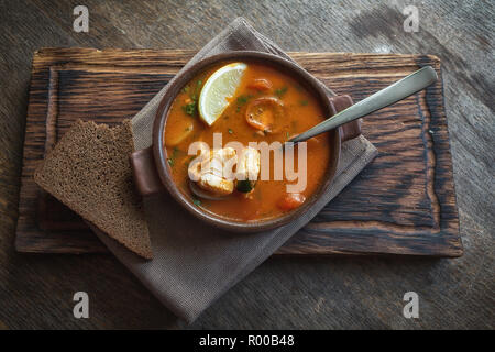 Marmitako soup in a ceramic bowl on a wooden board Stock Photo