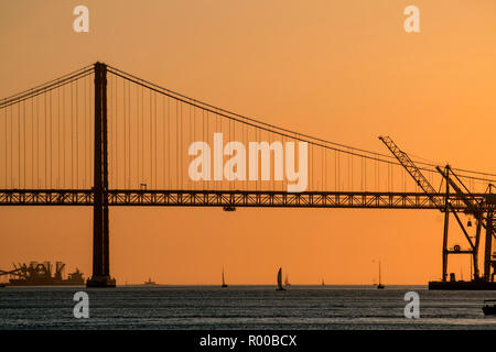 Evening atmosphere on the Tagus River (Rio Tejo) with sailboat and the Ponte 25 de Abril suspension bridge, Lisbon, Portugal. Stock Photo