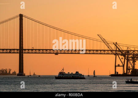 Evening atmosphere on the Tagus River (Rio Tejo) with ferry and the Ponte 25 de Abril suspension bridge, Lisbon, Portugal. Stock Photo