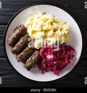 Beef rolls with mustard, bacon and pickles on a plate served with mashed potatoes and red cabbage close-up. top view from above Stock Photo