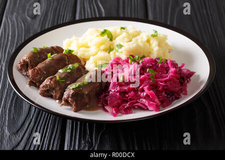 German Rouladen tender rolls of beef filled with pickles, onions, and bacon with mashed potatoes and red cabbage close-up on the table. Horizontal Stock Photo