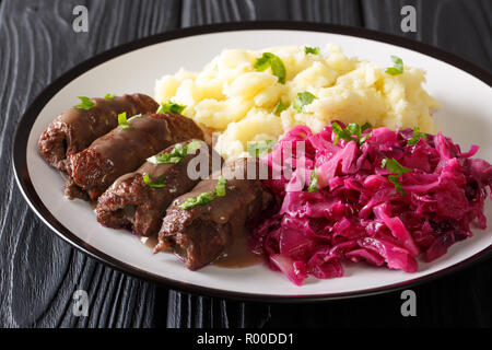 Beef rolls with mustard, bacon and pickles on a plate served with mashed potatoes and red cabbage close-up. horizontal Stock Photo