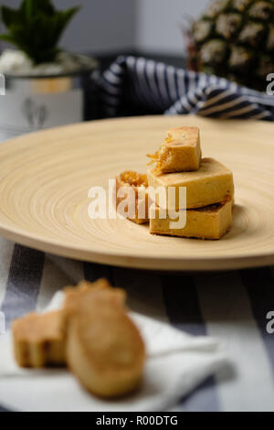 Brown cut chinese traditional pineapple cake bakes, placed with wood platefork, green plant, stripe cloth Stock Photo