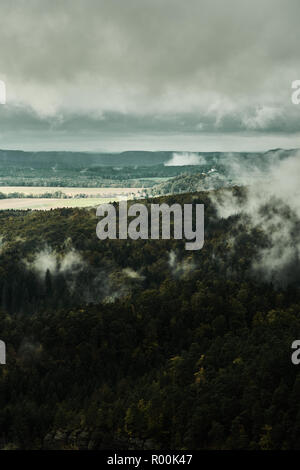 Deadpan dark misty rainy morning landscape with the sand rocky montains in Czech Saxon Switzerland in autumn colors. Stock Photo