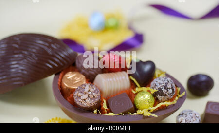 Close up composition with half dark Ester chocolate egg full of hand picked chocolates Stock Photo