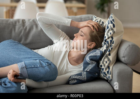 Unhappy woman lying on couch at home Stock Photo