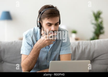 Man studying using computer and headset online Stock Photo