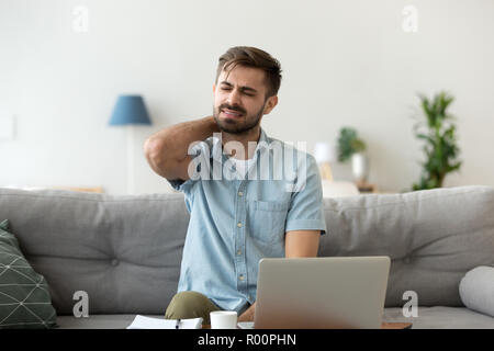 Man having neck pain sitting working at home Stock Photo