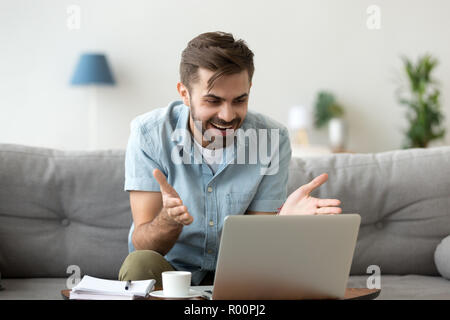 Surprised young man read news on laptop Stock Photo