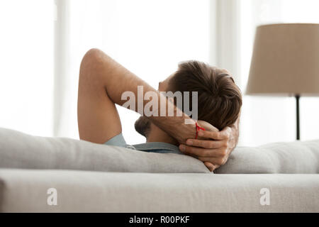 Male holding hands behind head rear view Stock Photo