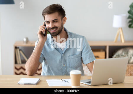 Man sitting at the desk using laptop talking by phone Stock Photo
