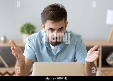 Frustrated man looking at computer screen sitting at the desk Stock Photo