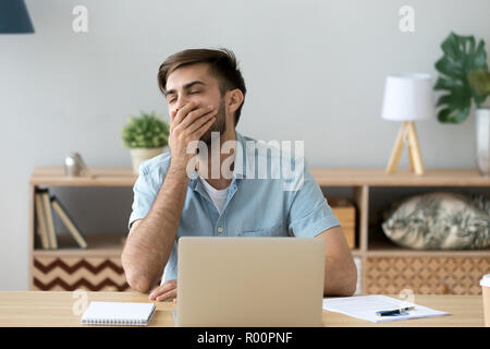 Bored young man sitting at the desk  Stock Photo