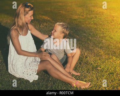 Mother and son in a fabulous garden sitting on a grass Stock Photo