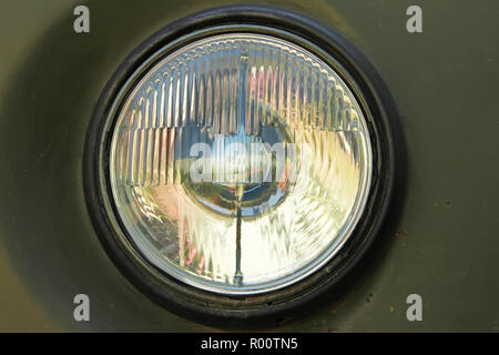 Old car round headlight against a dark green painted rusty body Stock Photo