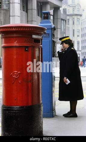 A traffic warden using a Police blue phone box. London, England, UK. Circa 1980's Stock Photo