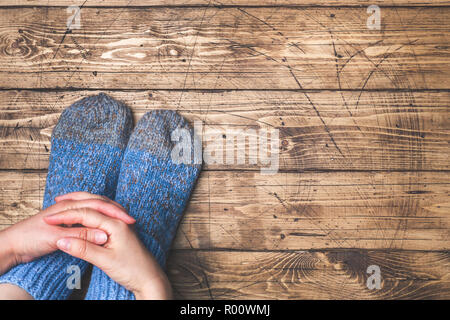 Legs in woolly knitted socks on wooden background Copy space Stock Photo