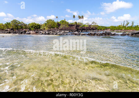 Wave in coral and sand shallow lagoon of Pohnpei, Micronesia, Oceania with overgrown Nan Madol prehistoric ruined in the background. Stock Photo