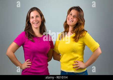 Two Happy Twin Sisters Smiling on Gray Background Stock Photo
