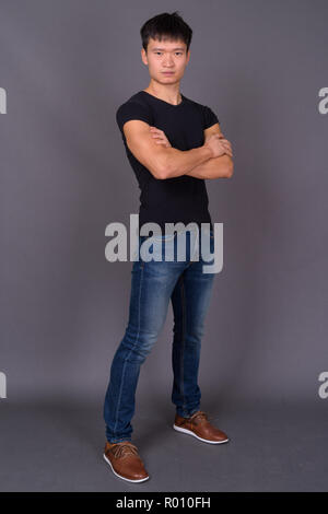 Studio shot of young Chinese man against gray background Stock Photo