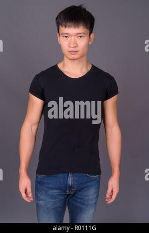 Studio shot of young Chinese man against gray background Stock Photo