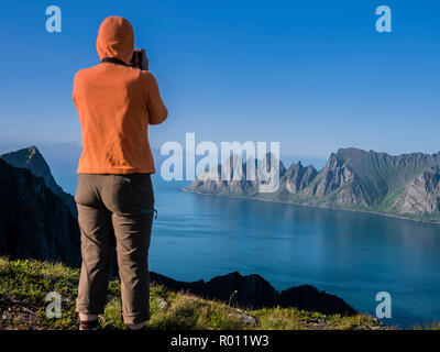 Photographer taking picture of panorama view, seen from mountain Husfjell to mountain range Okshornan,  island Senja, Troms, northern Norway, Norway Stock Photo