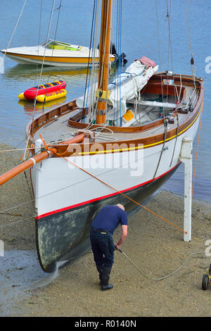 Power washing the hull of a Falmouth Working Boat on the beach at St Mawes, Roseland Peninsula, Cornwall, South West England, UK Stock Photo