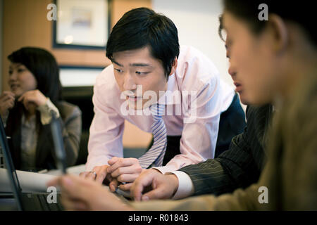 Young businessman using a laptop with two other colleagues. Stock Photo