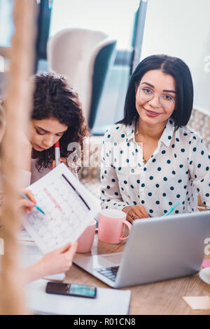 Delighted nice woman sitting in front of the laptop Stock Photo