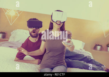 Cheerful couple watching TV in visual reality glasses Stock Photo