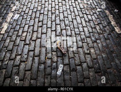 womens beaded slip on shoe discarded on dark cobbled street Stock Photo