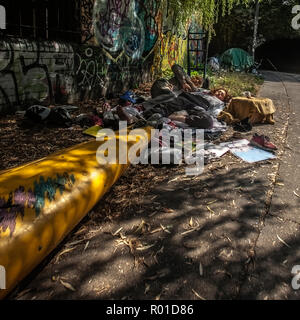 A homeless couple sleeping rough by regents canal next to a canoe Stock Photo