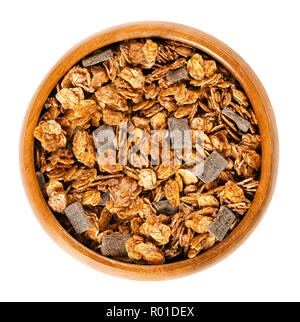 Crunchy chocolate granola in wooden bowl. Crispy cereals, made of rolled and toasted whole grain oat flakes, date juice and dark chocolate chunks. Stock Photo