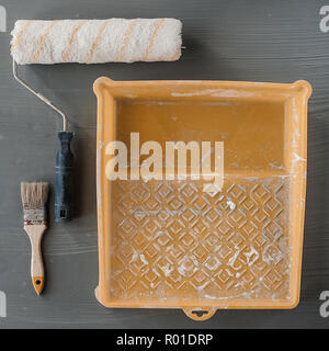 The object tools of paint worker concept, paint roll brush and white paint color in used plastic tray. Selective and soft focus for background. Stock Photo