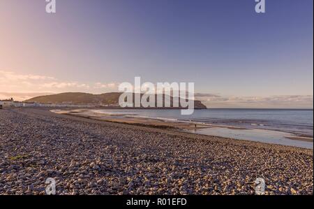 A view of Llandudno’s curving shoreline lined by white fronted hotels at dusk.  The Great Orme headland is in the distance and a fading blue sky is ab Stock Photo