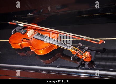 brown vintage violin with bow lying on a piano closeup indoor Stock Photo